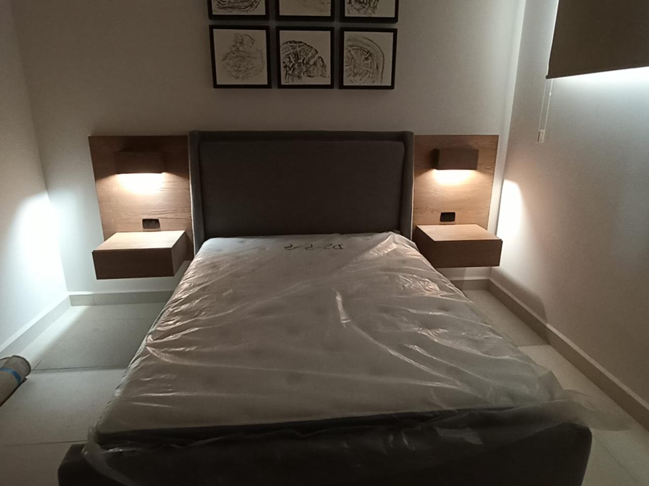 Recámara minimalista con cabecera y burós flotantes en madera